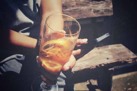 Glasses of brandy with smart phone on handの写真素材