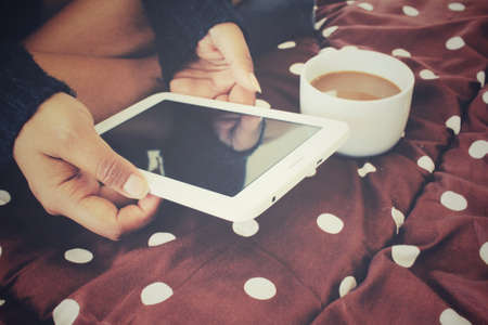 Tablet with coffee cup on the bedの写真素材