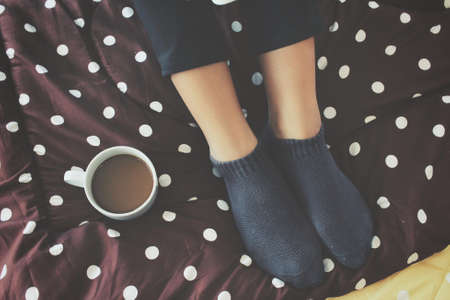 Woman drinking coffee on the bedの写真素材