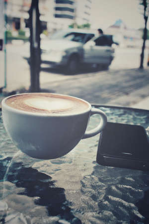 Vintage latte art coffee with smart phoneの写真素材
