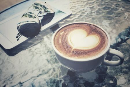 Vintage latte art coffee with tablet and sunglassの写真素材