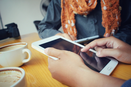Male and female couple with tablet sitting indoor in trendy urban cafe.の写真素材