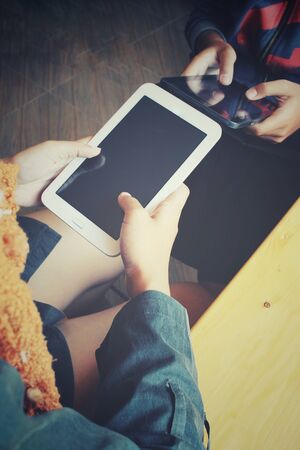 Male and female couple with tablet sitting indoor in trendy urban cafe.の写真素材