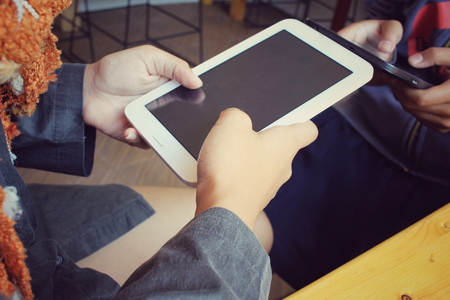 Male and female couple with tablet sitting indoor in trendy urban cafe.の写真素材