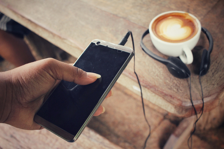Selfie of smart phone with earphone and coffee cupの写真素材