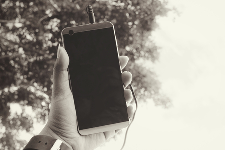 Woman listening to music on earphone with smart phone in the gardenの写真素材