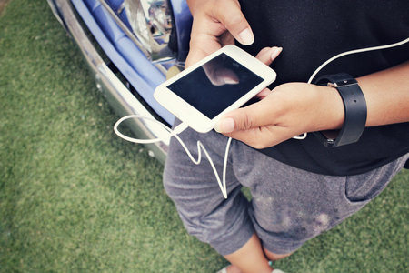 Woman listening to music on earphone with smart phone and old car