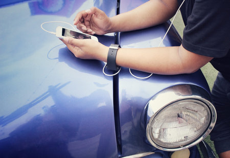 Woman listening to music on earphone with smart phone and old car