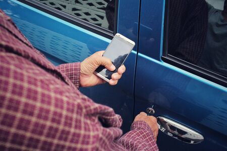 Man open the door car with smart phoneの写真素材