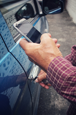 Man open the door car with smart phoneの写真素材
