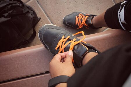Woman hands tying shoelaces with a backpackの写真素材