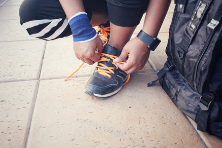 Woman hands tying shoelaces with a backpack