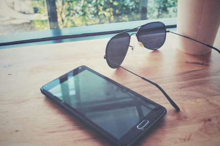 Iced coffee with smart phone and sunglass at cafeの写真素材