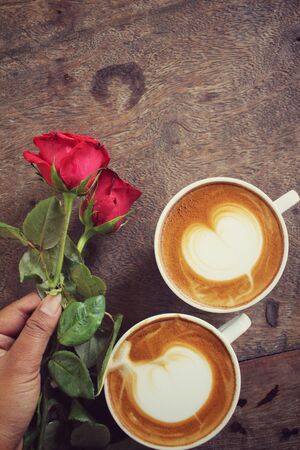 Two cups of latte art coffee with red roseの写真素材
