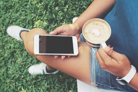 Woman drink coffee with smartphoneの写真素材