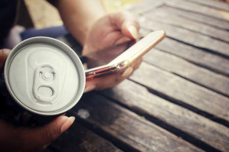 Woman using smart phone with aluminum canの写真素材
