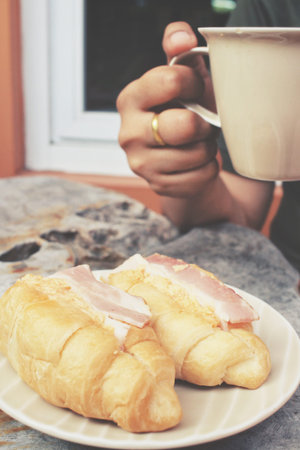 Woman drinking hot coffee with croissants