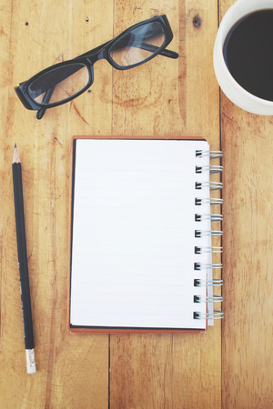 Blank notepad and pencil with coffee on office tableの写真素材