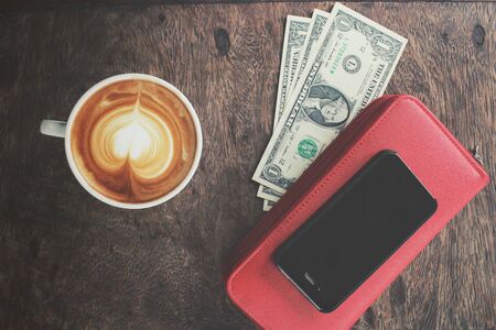 Vintage latte art coffee and smart phone with dollarsの写真素材