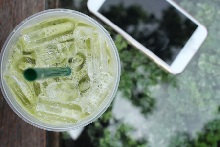 Iced green tea and milk with smart phoneの写真素材