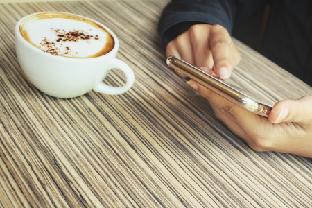Woman drink coffee with smart phoneの写真素材