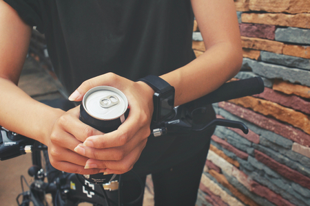 Woman drinking cola can with bikeの写真素材
