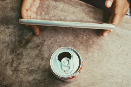 Using tablet with cola canの写真素材