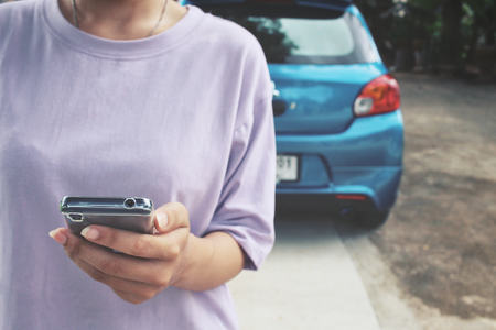 Woman using smart phone with carの写真素材