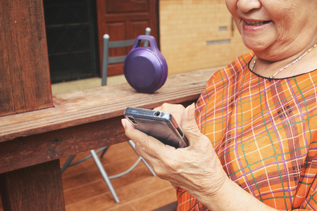 Senior woman using bluetooth speaker with smart phoneの写真素材