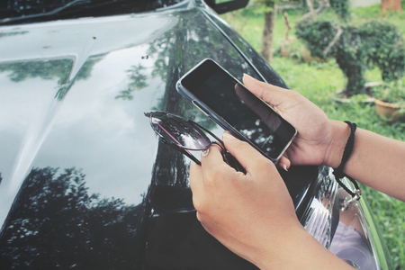 Woman using smart phone with carの写真素材
