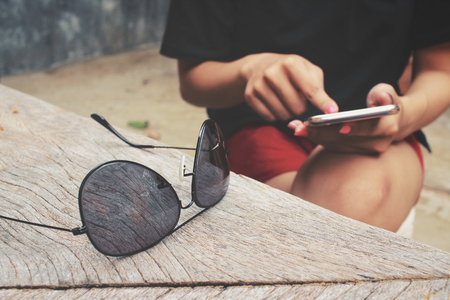 Woman using smart phone with sunglassesの写真素材