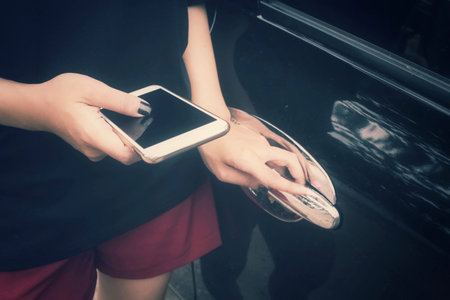 Woman using smart phone with car
