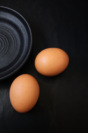 Egg with empty plate on black backgroundの写真素材