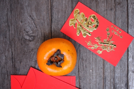 Red envelope in chinese new year festival with persimmons fruitの写真素材