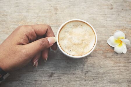 Selfie of coffee on hand with white frangipani flowerの写真素材