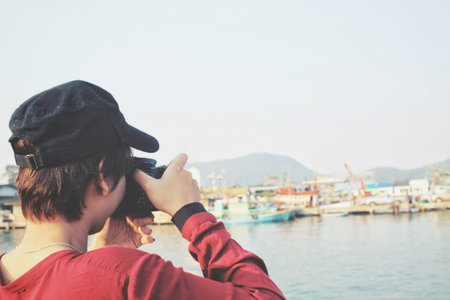 Woman using a camera to take photo with fishing boat