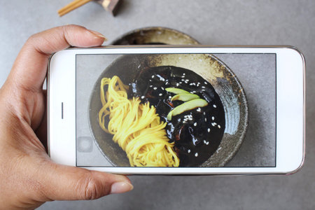 Taking a photo of korean black bean noodle with smart phoneの写真素材