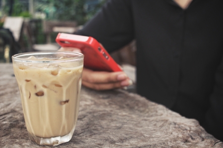 Woman using smart phone with iced coffeeの写真素材