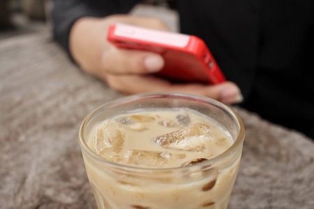 Woman using smart phone with iced coffeeの写真素材