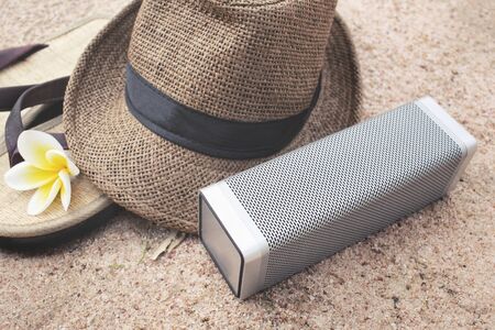 Flip flops with hat and wireless speaker on beachの写真素材