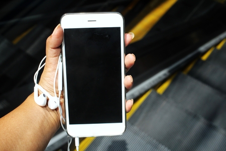 Smart phone and earphones on hand with staircasesの写真素材