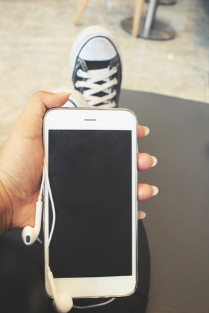 Smart phone and earphones on handの写真素材