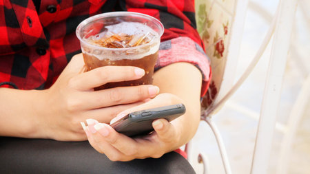 Woman drinking cola with using smart phoneの写真素材