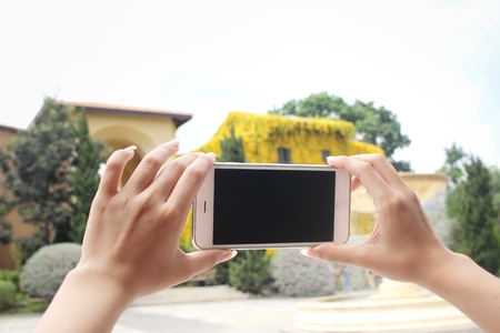 Woman using a smart phone to take photoの写真素材