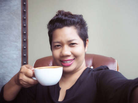 Selfie of woman drinking coffee with sneakersの写真素材