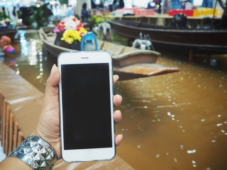 Smart phone on hand at floating market in Thailandの写真素材