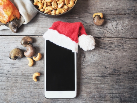 Smart phone with christmas hat and cashew nutsの写真素材