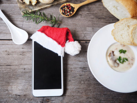 Smart phone with christmas hat and creamy mushroom soup