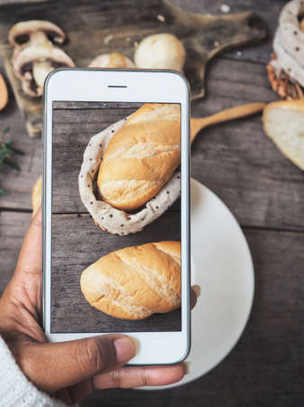 Taking a photo of crusty bread with smart phoneの写真素材