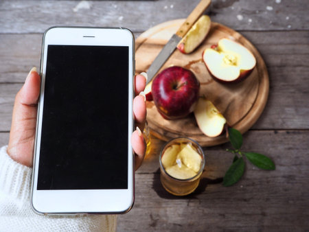 Apple juice with smart phone on handの写真素材